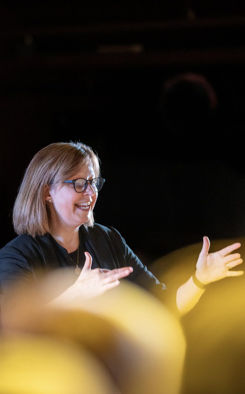 Cathy LaFrombois conducting, smiling, hands raised