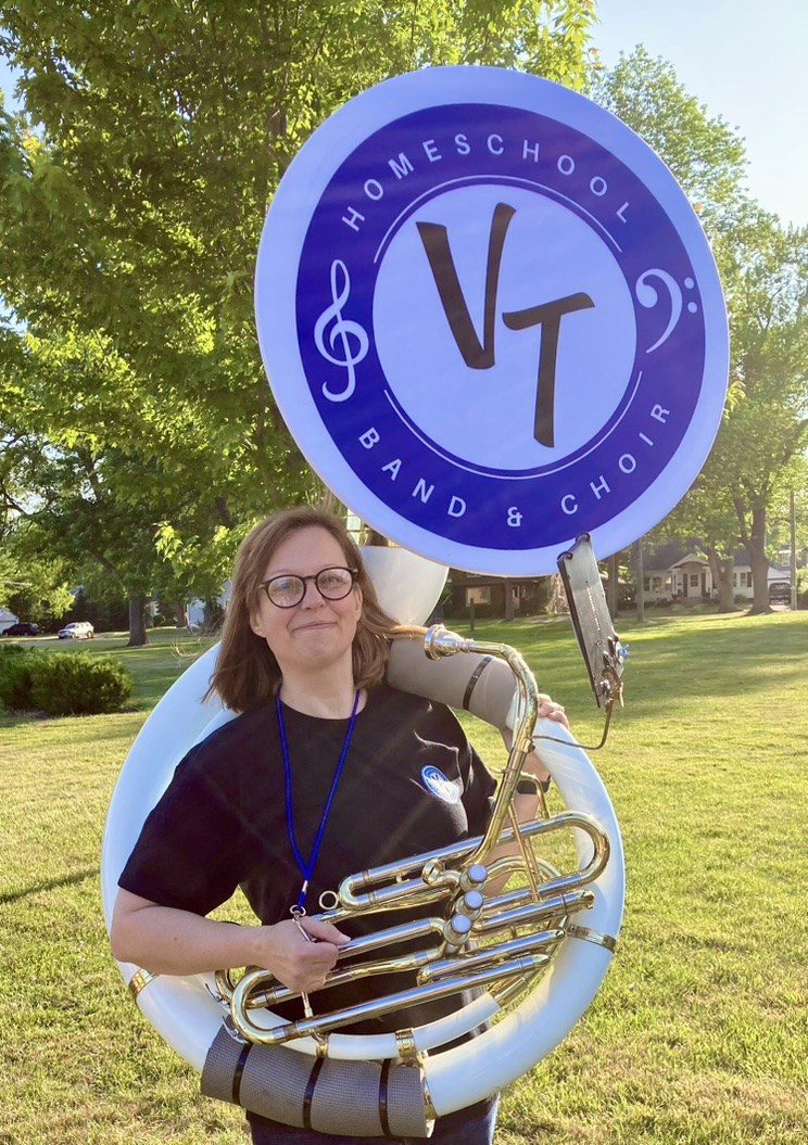 Cathy holding a sousaphone with a Valley Troubadours logo on the bell